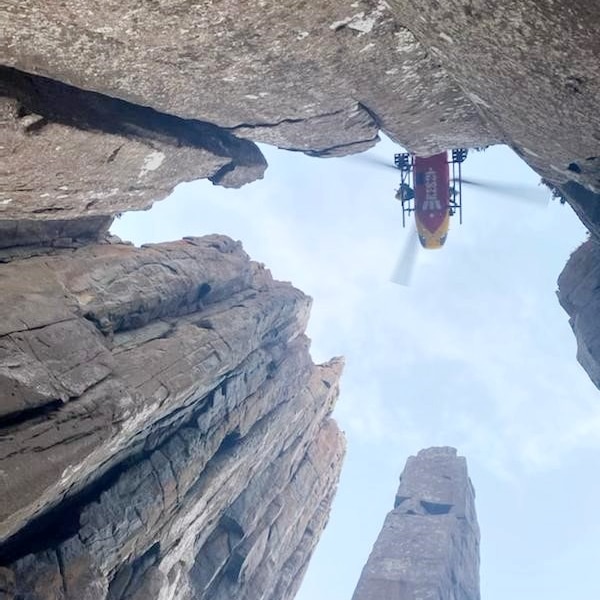 A helicopter hovers over towering rocks during a rescue