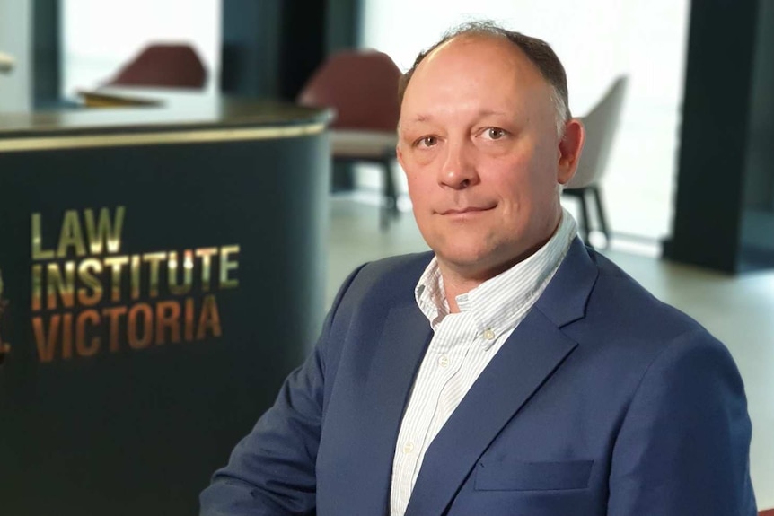 President of the Law Institute of Victoria, Stuart Webb, sits in an office in a blue jacket.