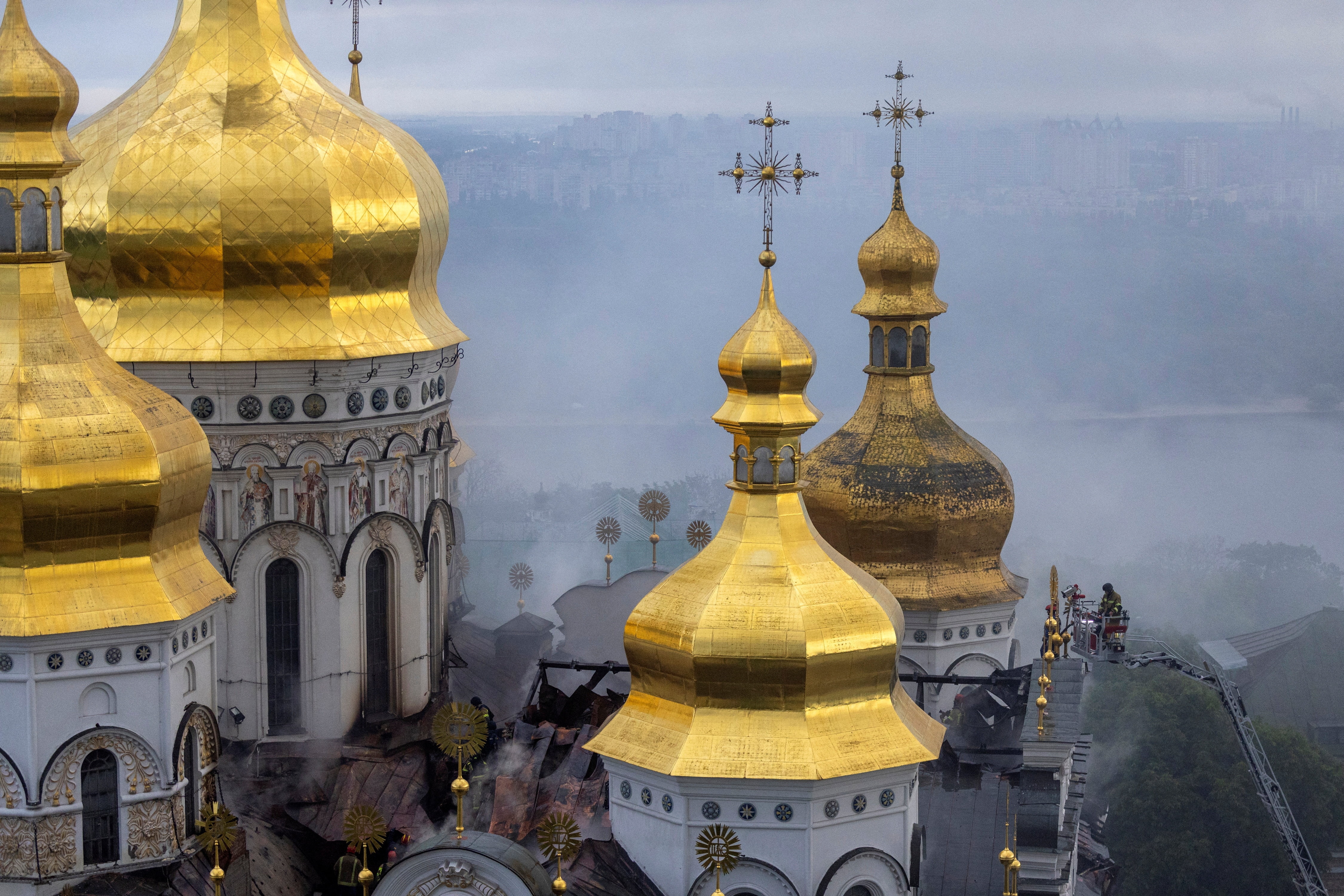 The golden domes of a cathedral simmering in smoke after a fire.