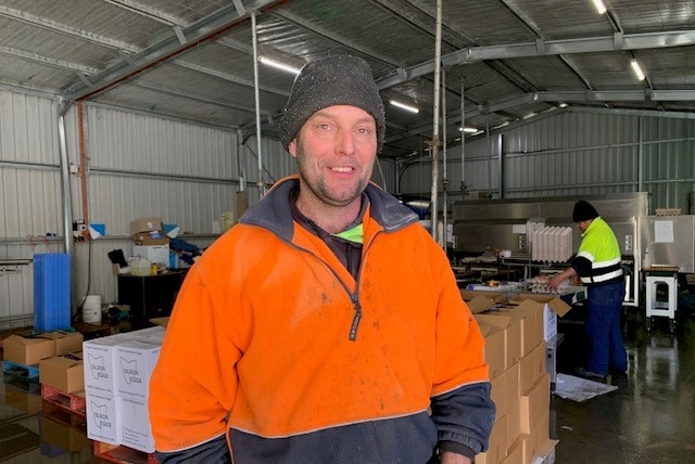 Man standing in front of boxes in an egg packing shed