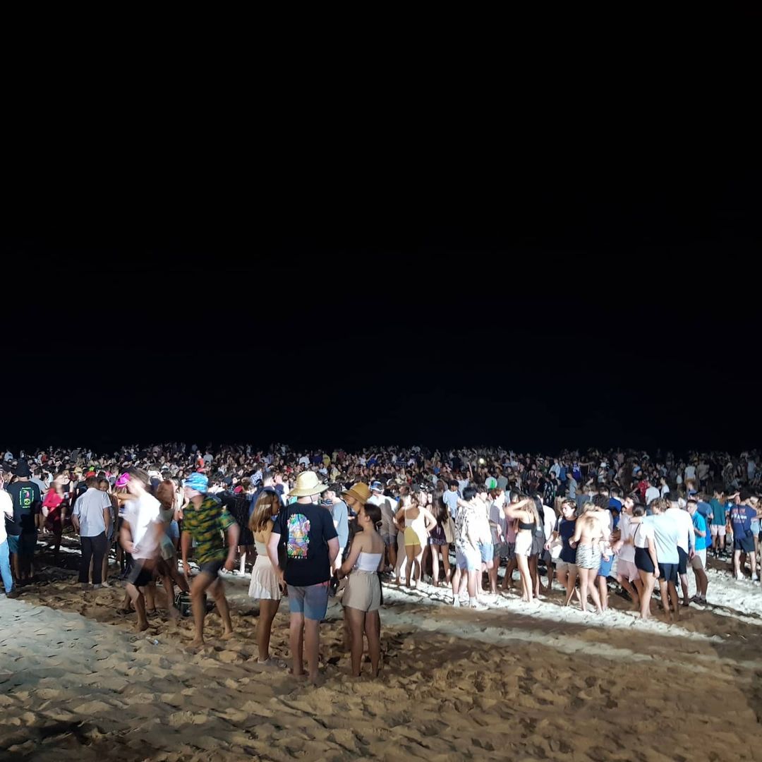 A big crowd of young people on a packed beach at night