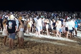 A big crowd of young people on a packed beach at night