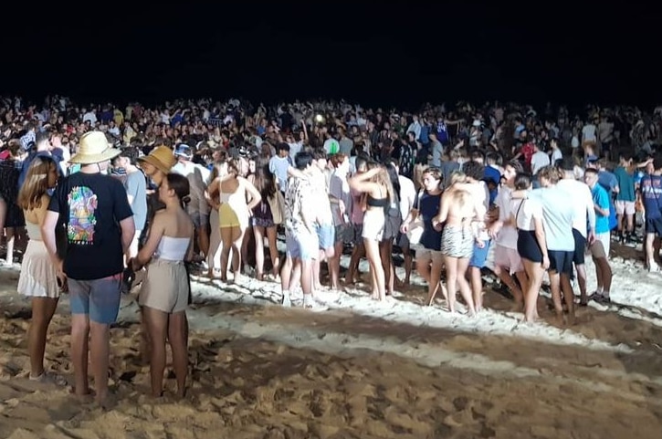 A big crowd of young people on a packed beach at night