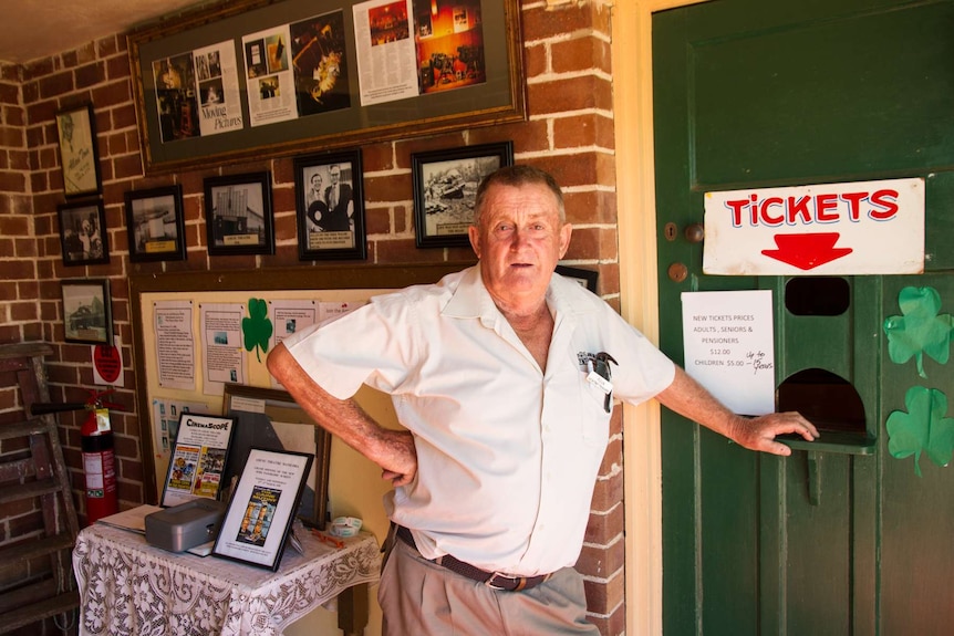 Man standing at door of ticket office at Amusu Theatre in Manildra, NSW.