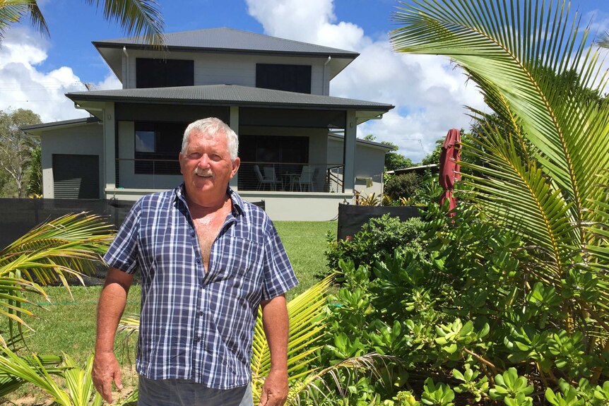 Man stands in front of two storey house on sunny day