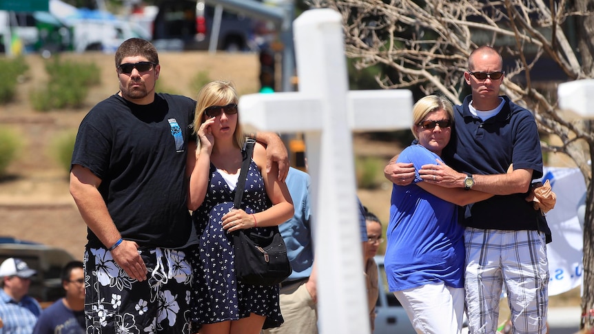 People stand at a memorial behind the theatre where a gunman opened fire on moviegoers in Aurora.