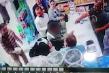 A still image from a security camera in a store when a man confronts two women and throws yoghurt on their hair.
