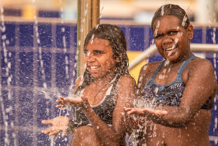 Two girls play with water at Leonora pool.