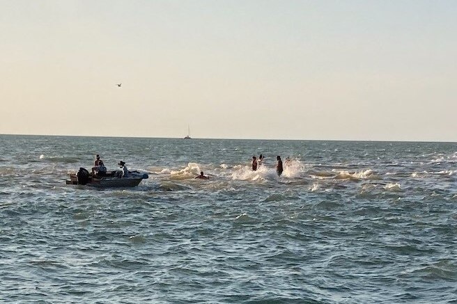 People dance in shallow water off the Darwin mainland.