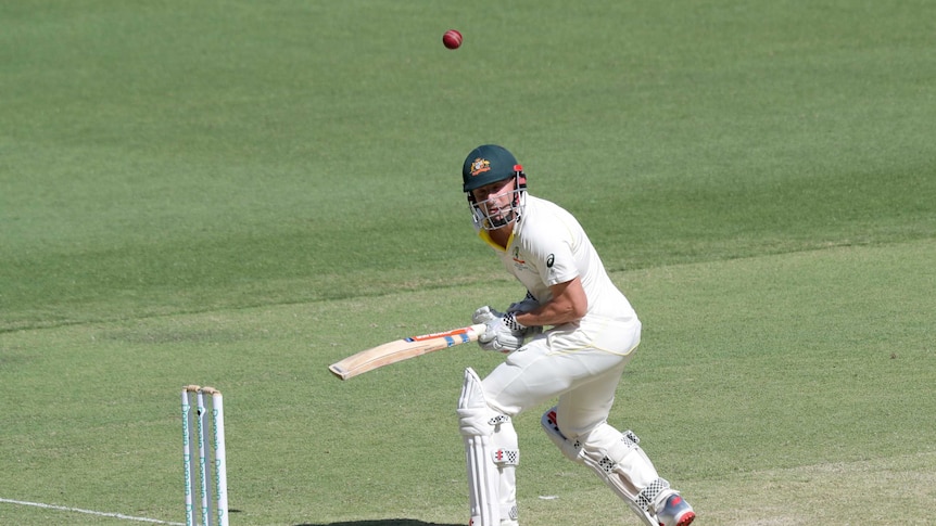 Australian batsman Shaun Marsh turns away from the cricket ball, which is flying away from him.