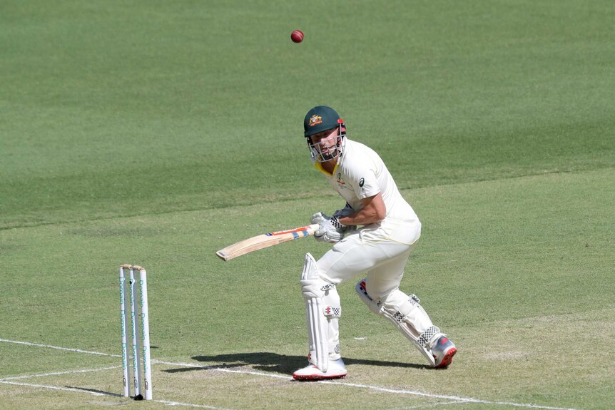 Australian batsman Shaun Marsh turns away from the cricket ball, which is flying away from him.