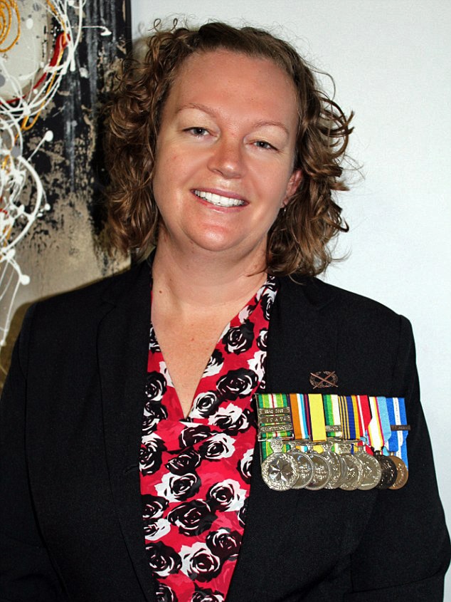 A woman in a red dress and blazer wears defence service medals