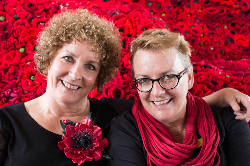 Lynn Berry and Deb Milligan surrounded by red crochet poppies