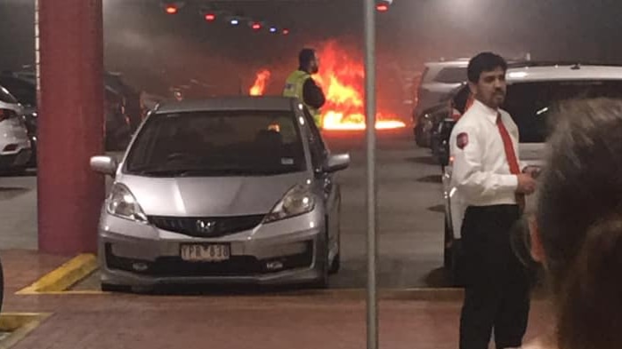 A car is aflame in an underground car park.