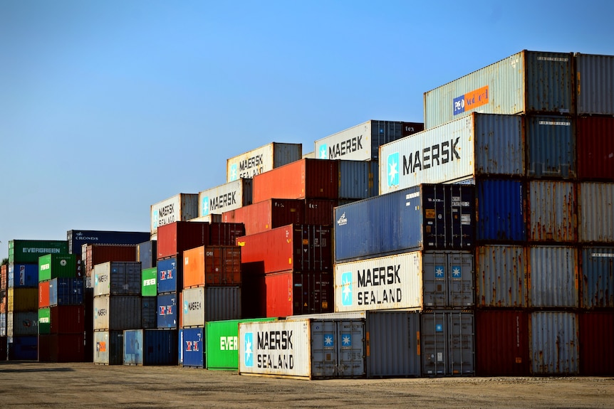 Large containers in different colours are stacked on top of each other in piles. Some say MAERSK SEALAND