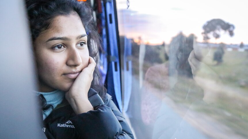 A young woman staring out a bus window.