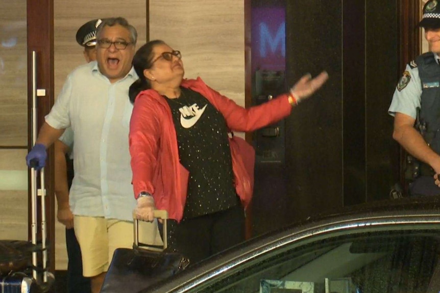 A man and a woman with big happy faces walk out of the hotel