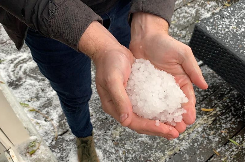 A person holds their hands out with hail stones morphed into a snow ball.
