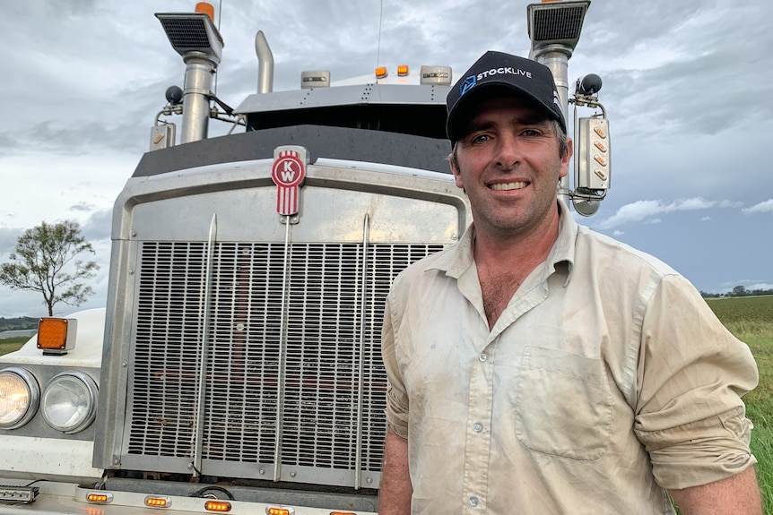 Man with hat stands in front of large truck