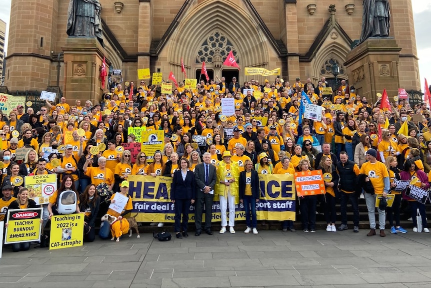 People standing in yellow outside a church holding signs 