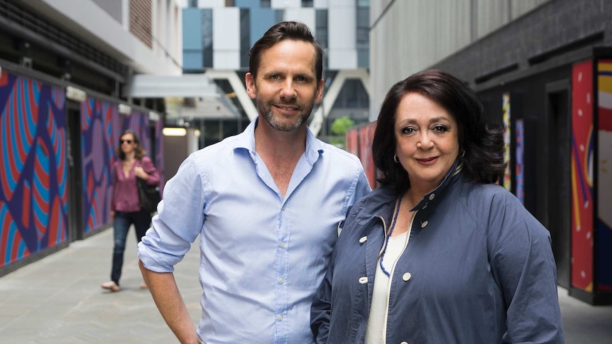 A man with short dark hair and a beard, and a woman with dark hair, standing in a Sydney laneway.