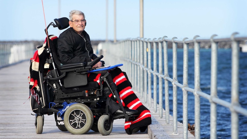 Man in wheelchair on jetty with ocean behind