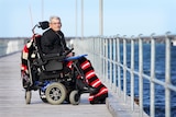 Man in wheelchair on jetty with ocean behind