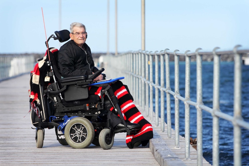 Man in wheelchair on jetty with ocean behind