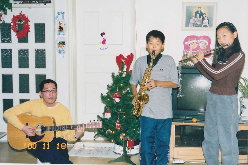 Dami Im playing flute with brother on sax and uncle on guitar