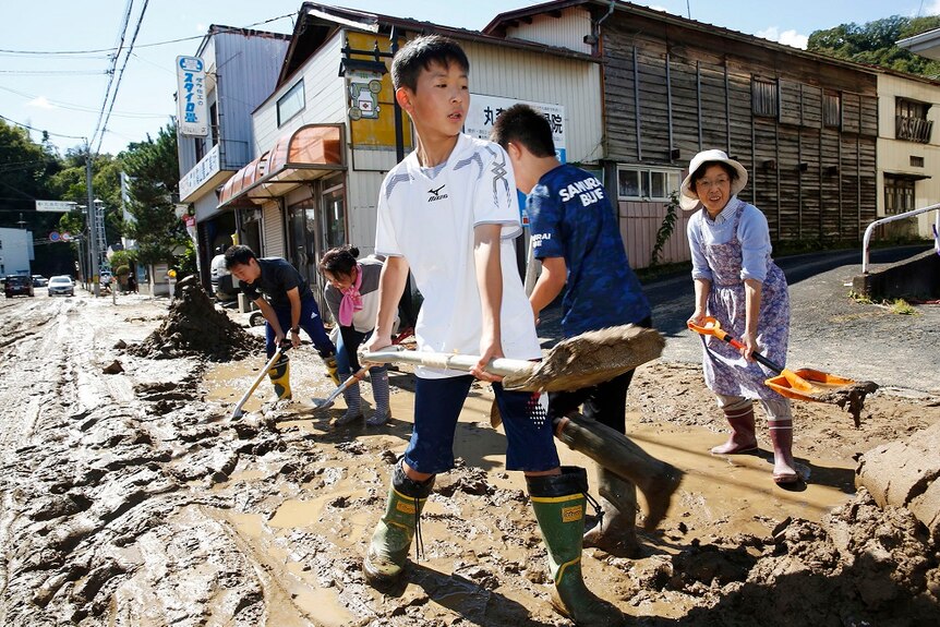 students and residents cleaning up mud from the streets after Typhoon Hagibis