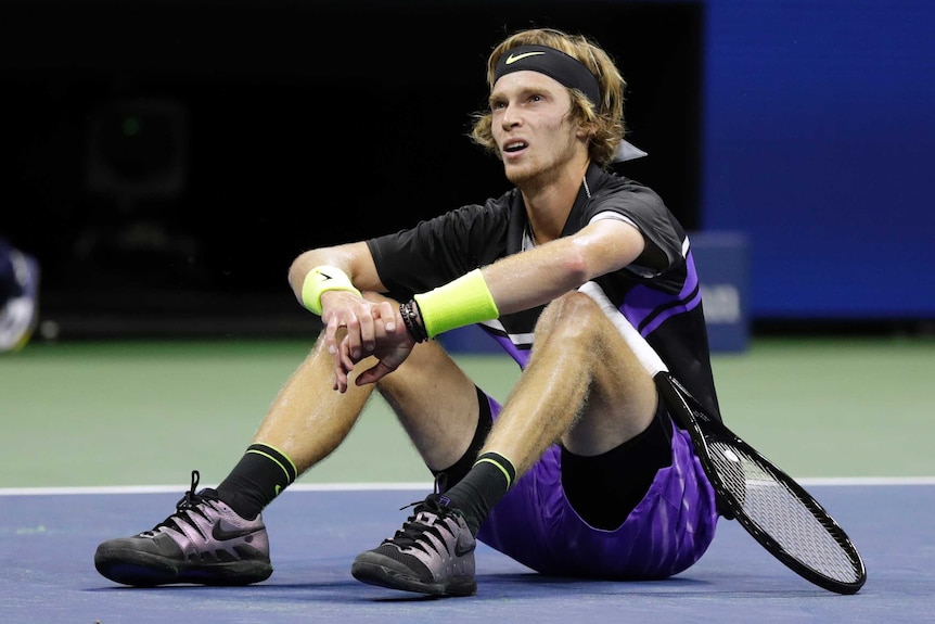 A tennis player sits on the court after being wrong-footed in a point at the US Open.