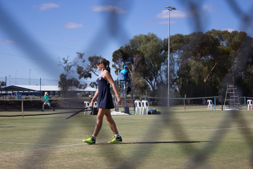 A player on a tennis court seen behind fence wire.