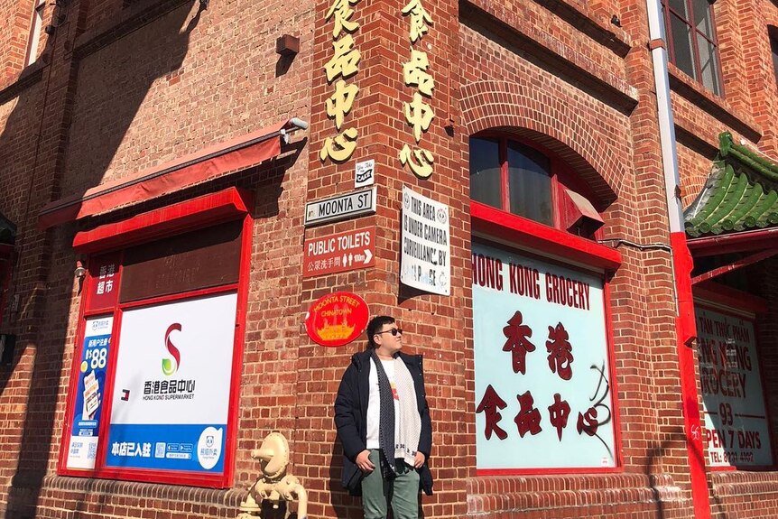 A man standing in front of a red-brick building