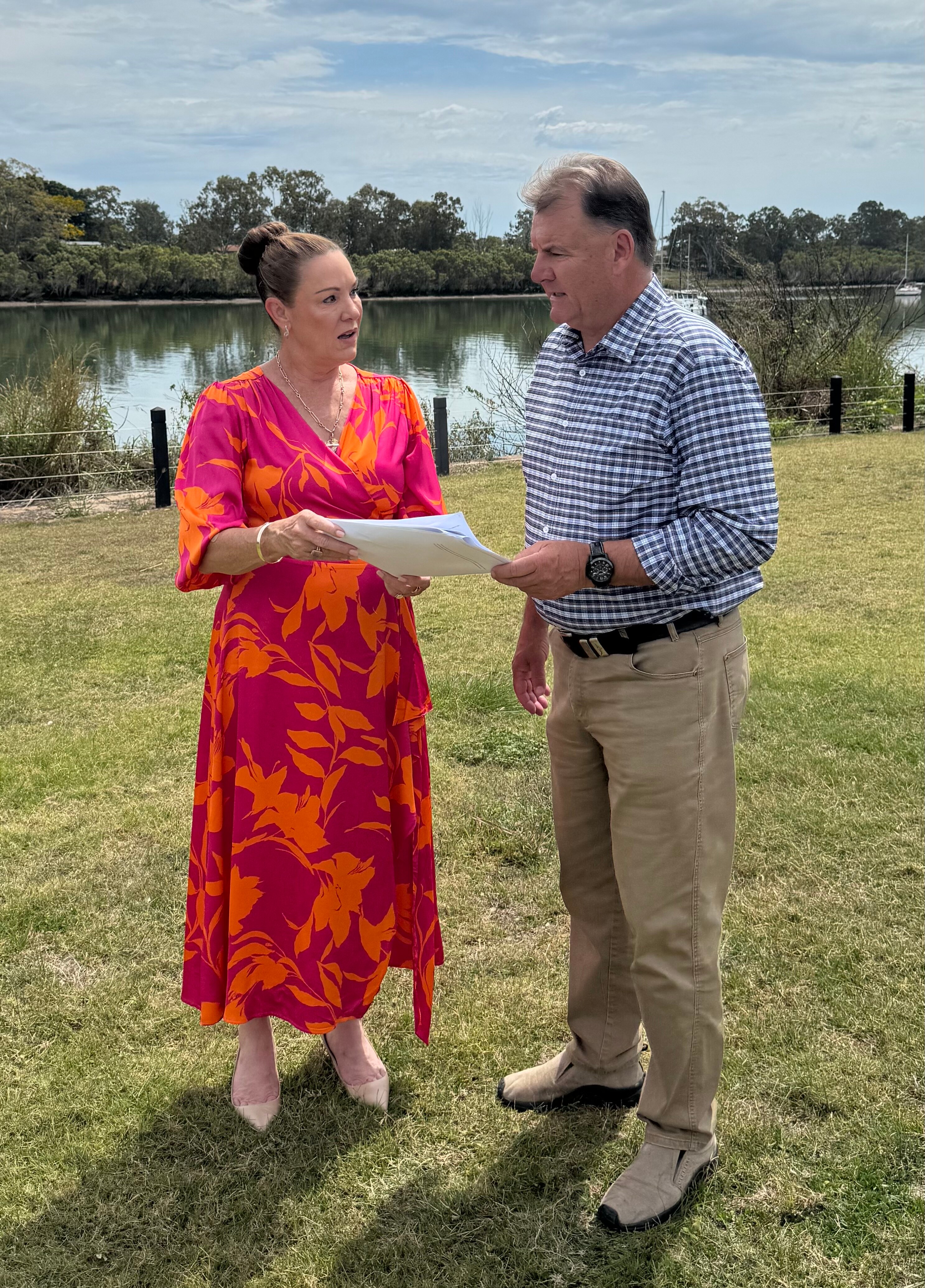 A woman and a man standing together in a park holding a letter