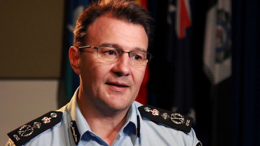 AFP Commissioner Reece Kershaw, in a uniform with flags hanging behind him in a room, speaks during an interview.