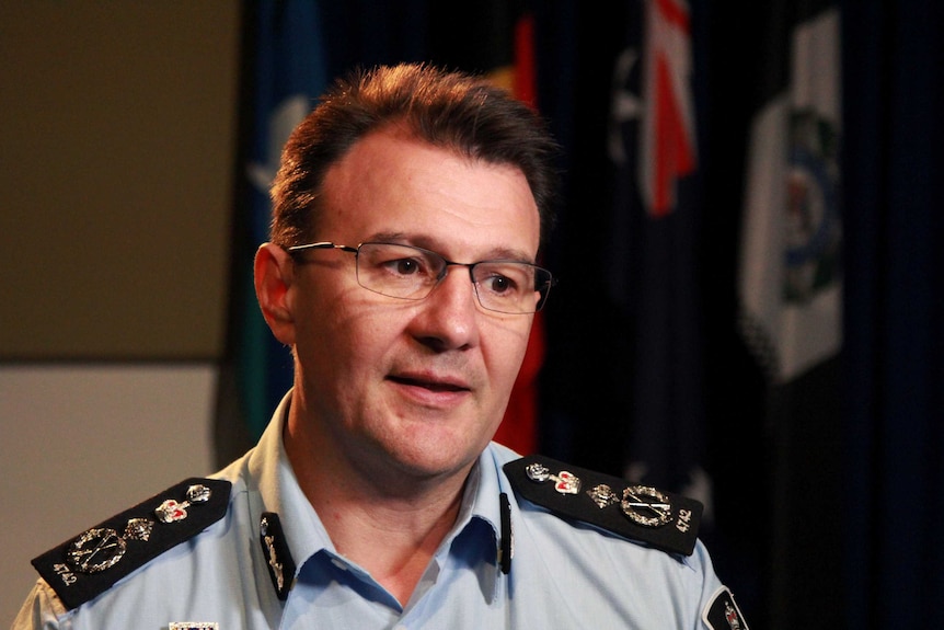 AFP Commissioner Reece Kershaw, in a uniform with flags hanging behind him in a room, speaks during an interview.