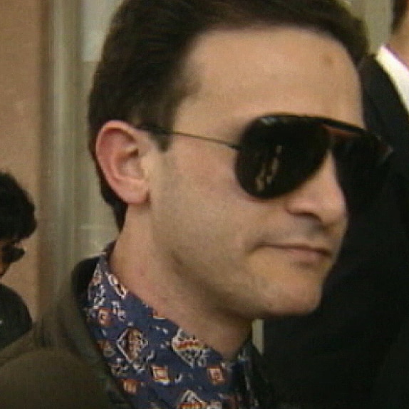 Domenic Perre pictured during the 1990s, with slicked back hair, a patterned blue shirt and aviator shades