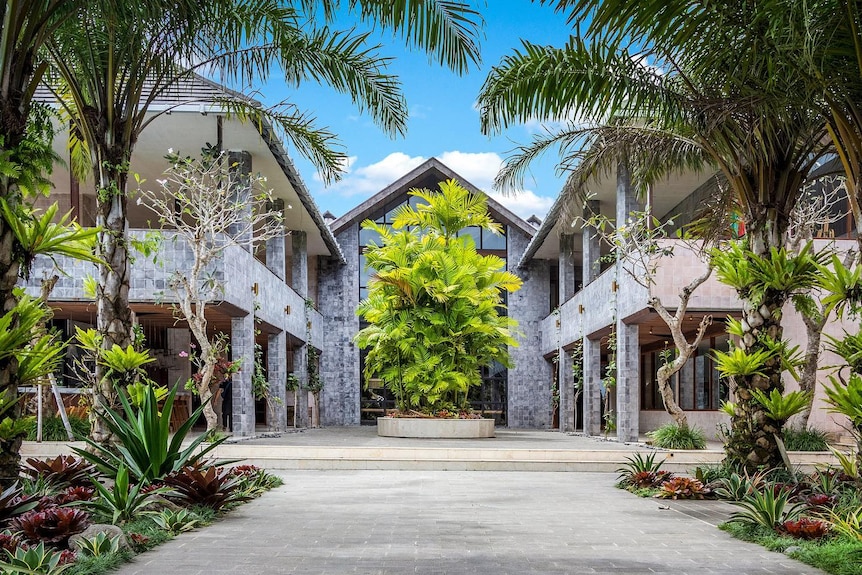 Two story concrete buildings with palm trees at the entrance. 