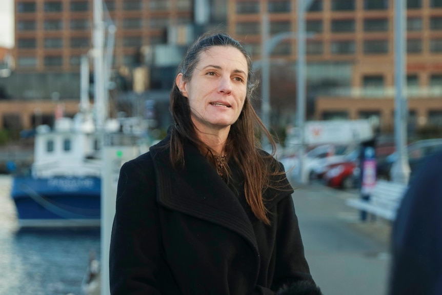 A woman standing on a wharf with fishing boats in the background