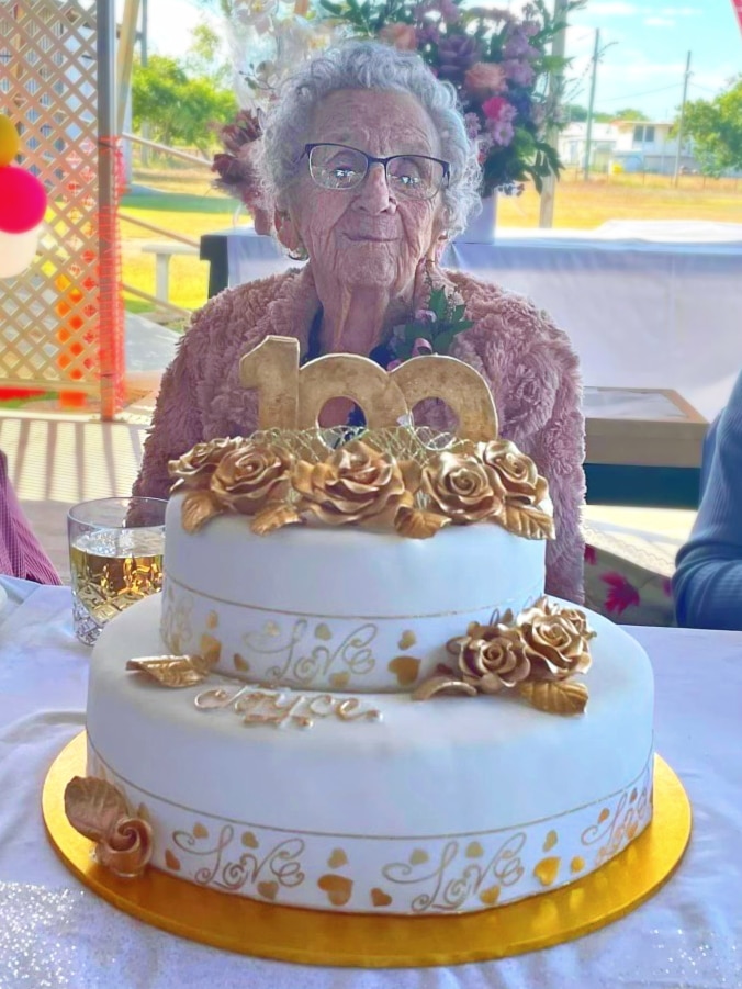 An elderly woman with a birthday cake.