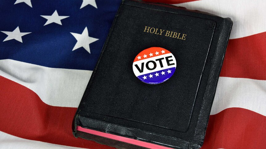 Vote pin and Holy Bible on American flag.