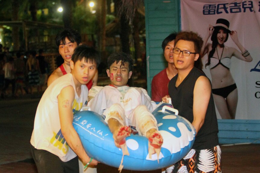 People carry an injured man at an amusement park in Taiwan after a fire and explosion