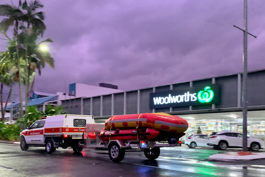 A QFES ute driving past the woolworths with purple cloudy skies.