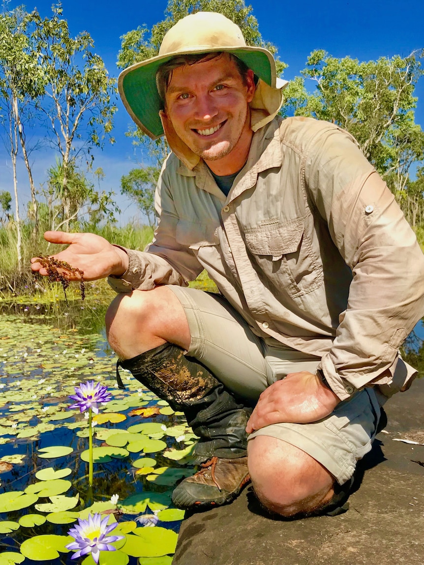 A man sitting near a pond. 