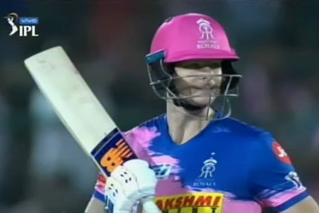 Steve Smith stands holding his bat across his chest by his shoulder wearing a pink batting helmet