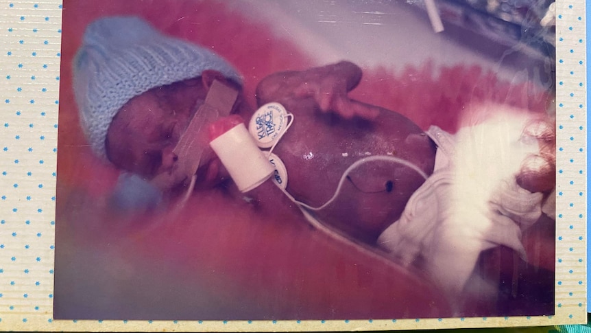 Newborn Jonathon wearing a blue beanie. 