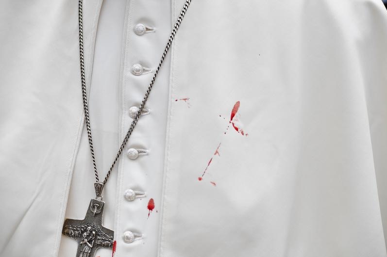 A few droplets of blood stain Pope Francis' white tunic