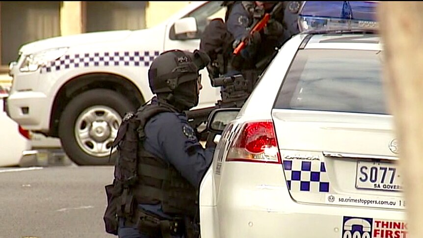 Police watch for a suspect near the Public Schools Club in Adelaide.