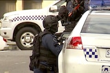 Police watch for a suspect near the Public Schools Club in Adelaide.