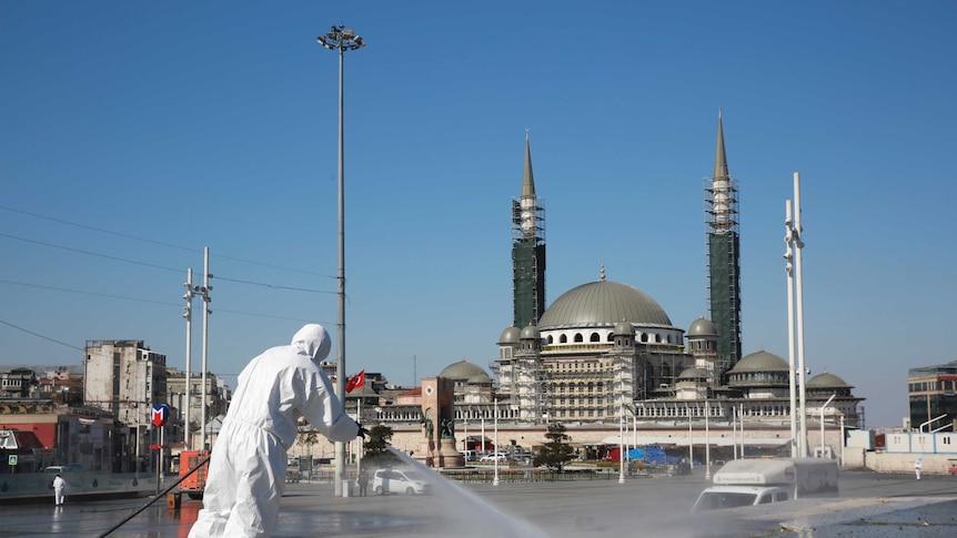 Workers clean and disinfect surfaces in front of a mosque in Istanbul's iconic Taksim Square.